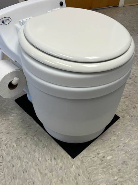 Laveo Dry Flush toilet on non-skid silicone mat by Cabin Depot, providing extra grip without solid mounting.